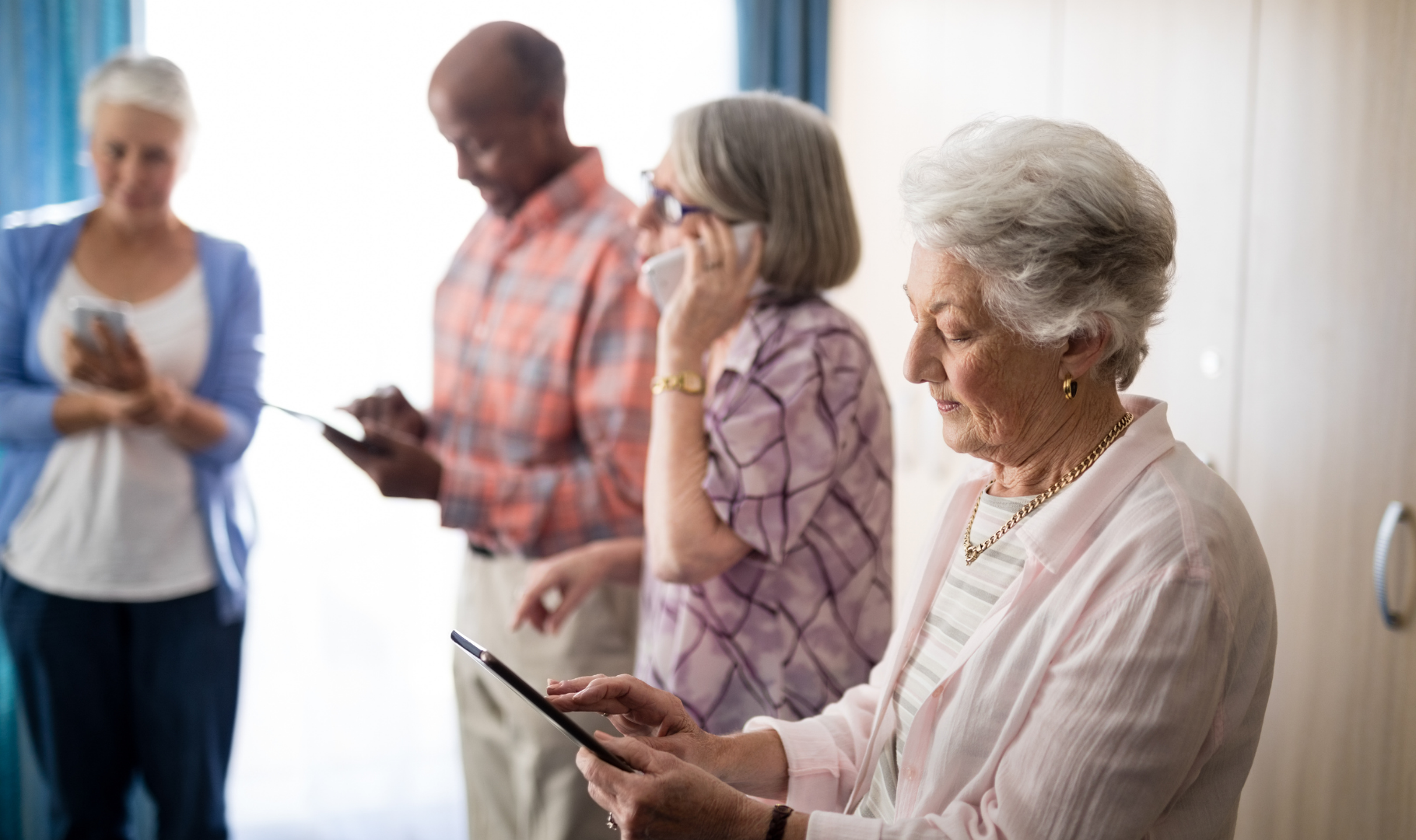 Four senior citizens using digital devices.