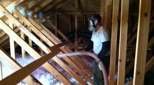 Person spraying insulation into an attic